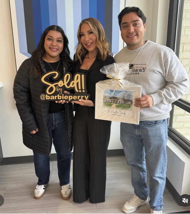 The Pasillas family with Barbie, holding a Sold sign and a watercolor of their new home
