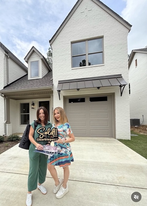 Barbie and a client with a Sold sign in front of a new townhome
