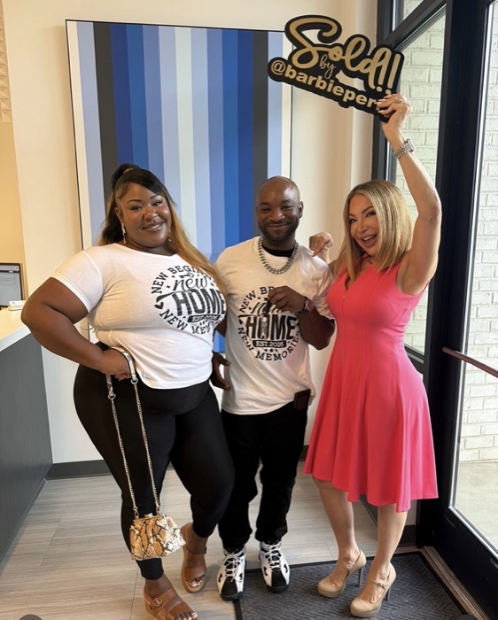 A couple in New Home shirts holding their keys with Barbie
